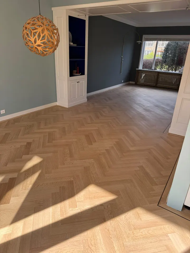 Dezelfde kamer met visgraat na het schuren, het parket licht en egaal in de zon