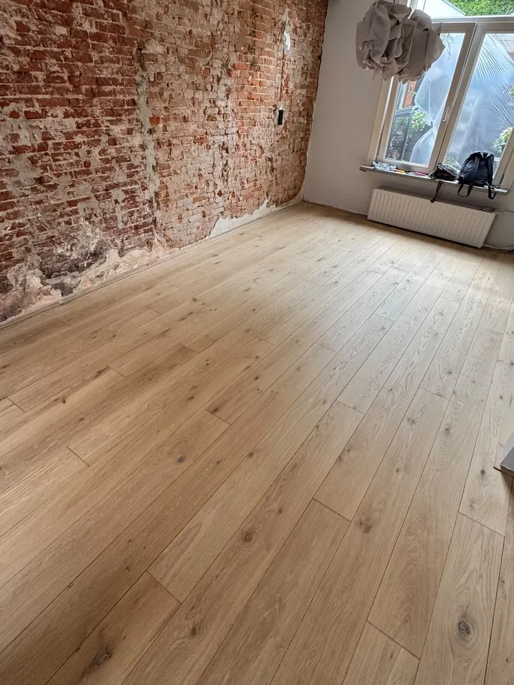 Dezelfde kamer na het schuren, de eiken planken licht en egaal van de bakstenen muur tot aan het raam