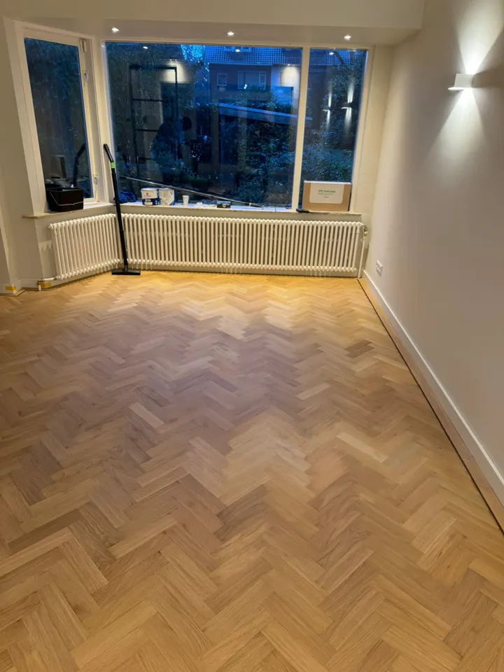 Eiken visgraatparket in een kamer met erker, warm in het avondlicht