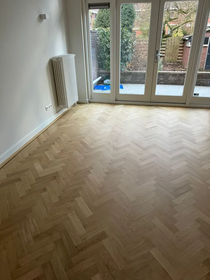 Licht eiken visgraatparket dat doorloopt tot aan openslaande deuren naar de tuin