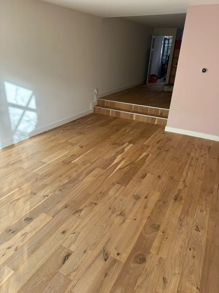 De twee treden tussen de roze kamer en de gang, afgewerkt in hetzelfde eiken met noesten als de vloer