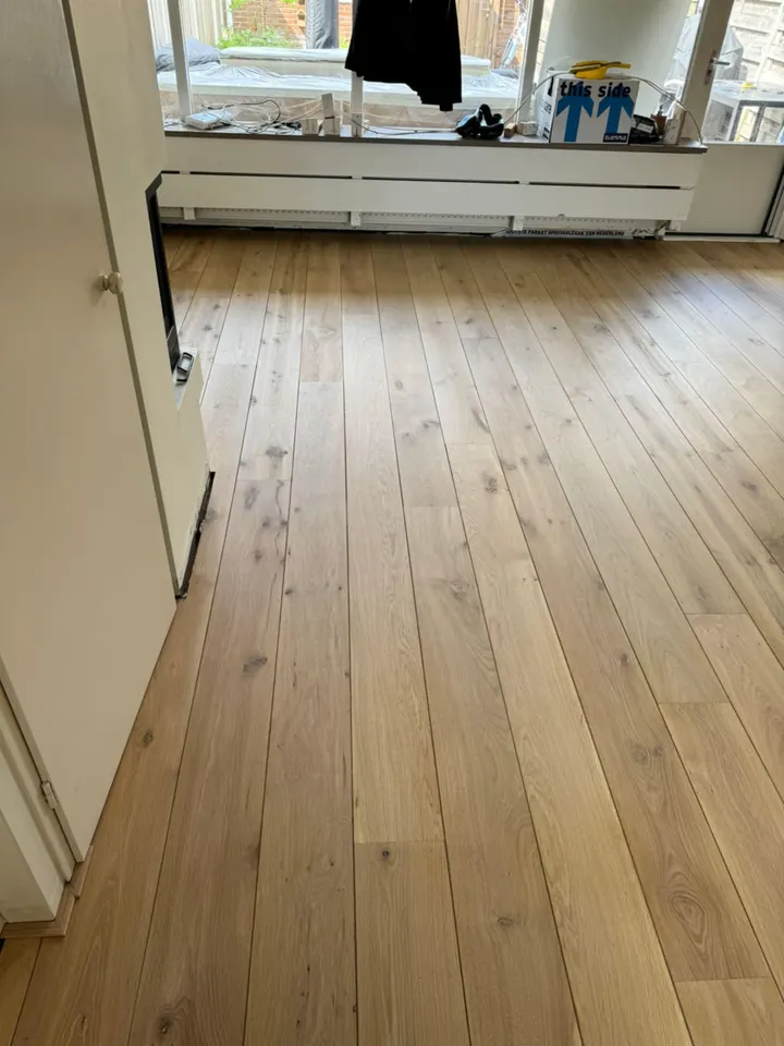 Licht eiken plankenvloer die naar de tuindeuren loopt, nog in de afwerkfase
